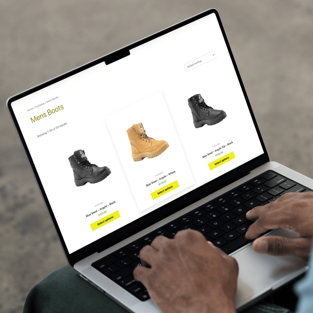 An individual using an ecommerce website design on a laptop with a pair of boots.