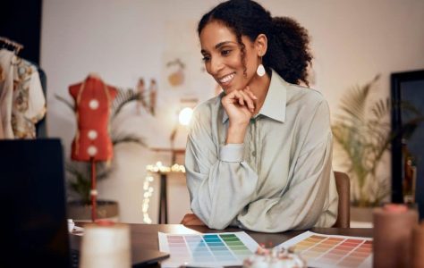 A woman sitting at a desk with a laptop and color swatches.