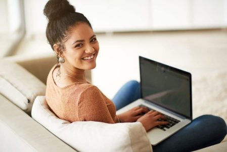 A young woman build a strong online presence by using a laptop on a couch.