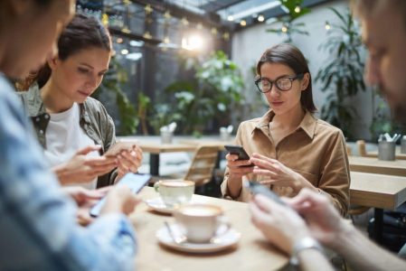 A group of people sitting around a table looking at their phones.