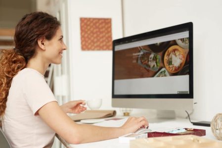 A woman sitting in front of a computer looking at a menu.